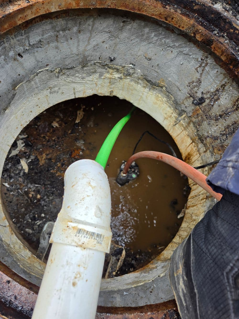 View of a sewer drain with visible pipes and water, showcasing maintenance work in progress.