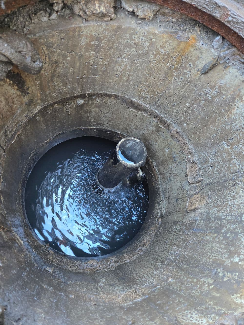 Close-up of a circular drain with water swirling inside a concrete base.