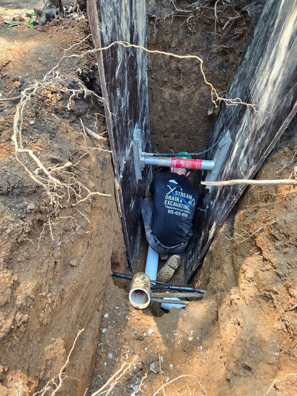 Excavation site showing a pipe installation with supports in a dirt trench.